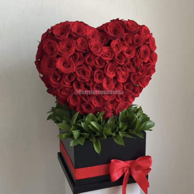 Heart-shaped arrangement of red roses in a black box with a red ribbon