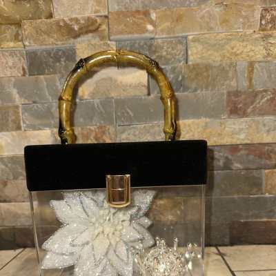 Clear handbag with a glittery white flower and silver crown inside