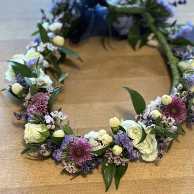Floral wreath with white, purple, and pink blooms on a wooden surface