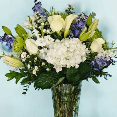 White and blue floral arrangement in a clear glass vase