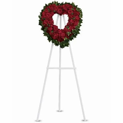 Heart-shaped red rose wreath on a white easel stand