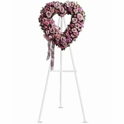 Heart-shaped pink rose wreath on a white easel with ribbon