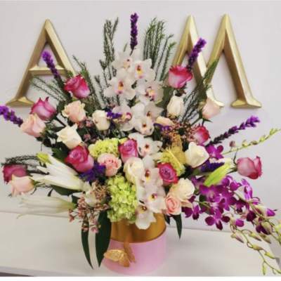 Mixed bouquet in a pink and gold vase with orchids and roses