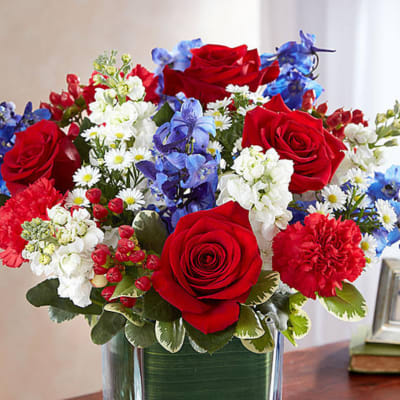 Red, white, and blue flower arrangement in a square glass vase