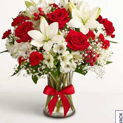 Red roses and white lilies in a glass vase with a red ribbon
