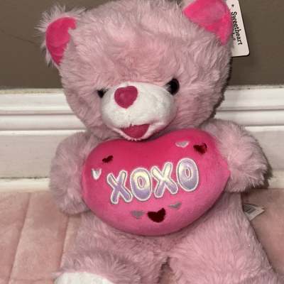 Pink teddy bear holding a heart-shaped pillow with "XOXO" text