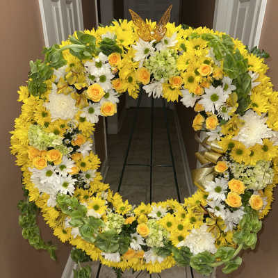 Large yellow and white floral wreath on a stand