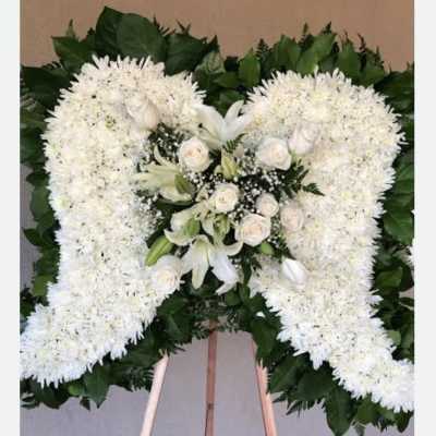 White floral funeral spray on an easel with a cross shape
