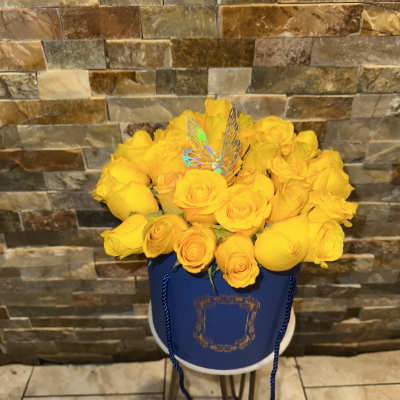 Yellow roses arranged in a blue hatbox with a butterfly pick