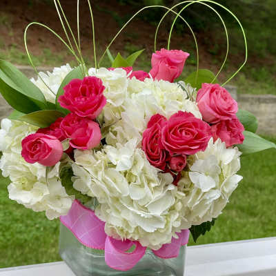 Pink roses and white hydrangeas in a glass vase with ribbon