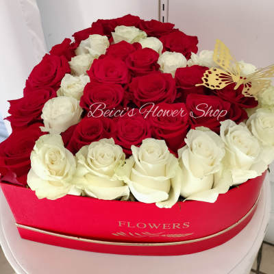 Red and white roses arranged in a heart-shaped box with a butterfly decoration
