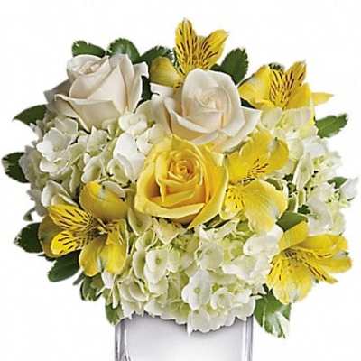 Yellow and white floral arrangement in a clear square vase
