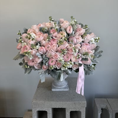 Large pink rose bouquet in a clear vase with a ribbon