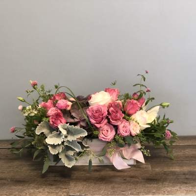 Pink and white rose arrangement in a low rectangular box with a ribbon
