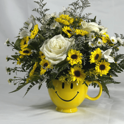 Yellow smiley-face mug holding white roses and yellow daisies