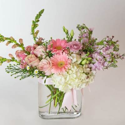 Pink and white mixed bouquet in a clear glass vase with a ribbon
