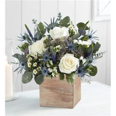 White roses and blue thistle in a wooden box centerpiece.