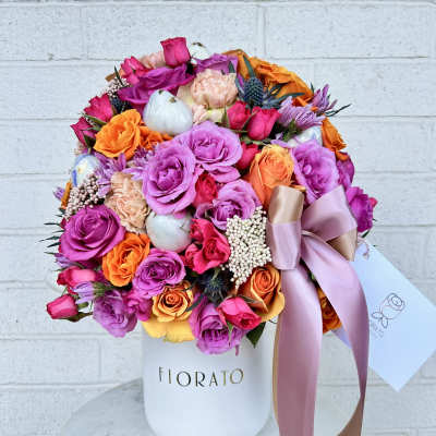 Mixed bouquet of pink, purple, and orange roses in a white hat box with ribbon
