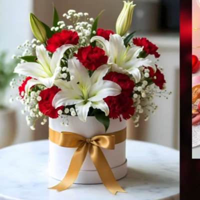 White lilies and red carnations in a round box with a gold ribbon