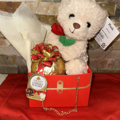 Teddy bear in a gift box with a wrapped chocolate and ribbon