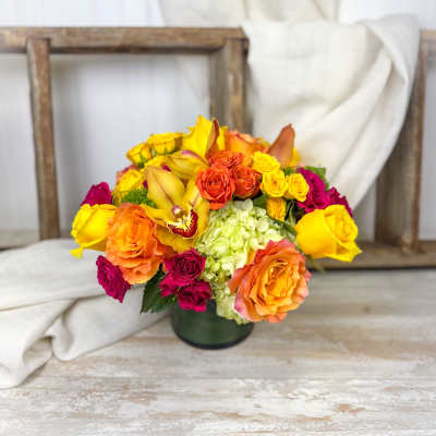 Bouquet of yellow, orange, and pink roses in a dark vase