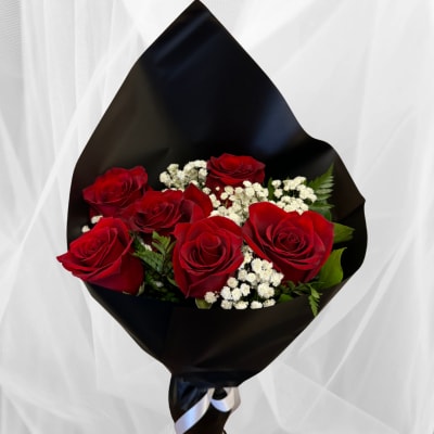 Bouquet of red roses with white filler flowers wrapped in black paper and ribbon