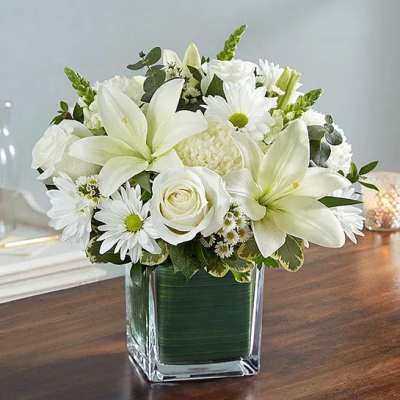 White lilies and daisies arranged in a square glass vase