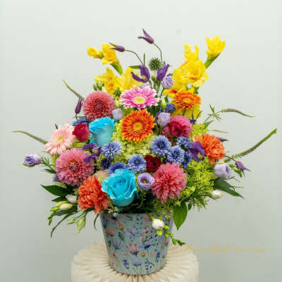 Colorful mixed flower arrangement in a floral tin container