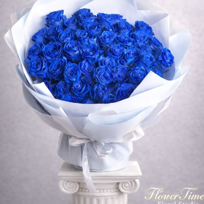 Bouquet of vivid blue roses wrapped in white paper