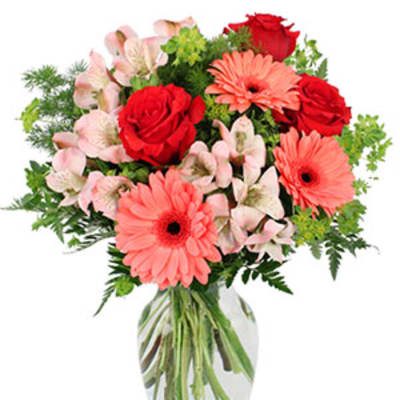 Bouquet of red roses, pink gerbera daisies, and pale alstroemeria in a glass vase