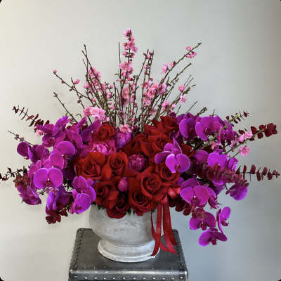 Red roses and purple orchids in a white vase with pink blossoms