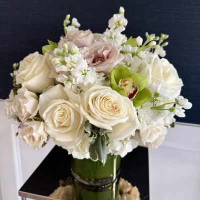 Cream roses and white flowers arranged in a glass vase