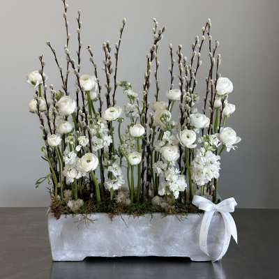 White floral arrangement with tall pussy willow branches in a rectangular container
