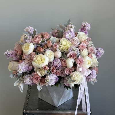 Large pastel bouquet of roses, peonies, and lilac flowers in a silver wrap