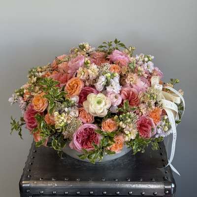 Large pink and peach floral arrangement in a low round container