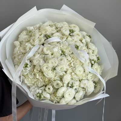 Large bouquet of white flowers wrapped in white paper with ribbon