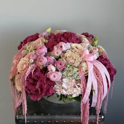 Pink and cream floral arrangement with roses and hydrangeas in a low container