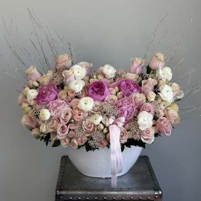 Large pink and white rose arrangement in a white bowl vase