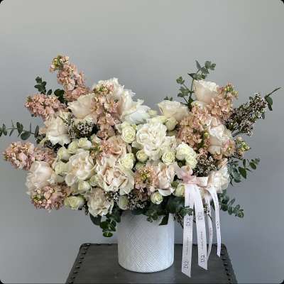 Large bouquet of cream and blush roses in a white textured vase