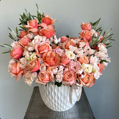 Large peach and blush rose arrangement in a white vase