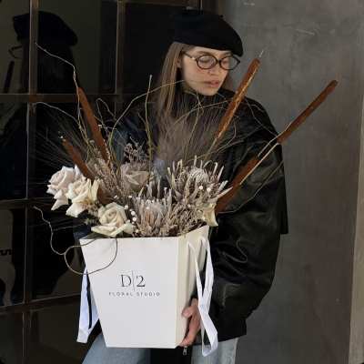 Bouquet of pale roses and dried botanicals in a white gift box