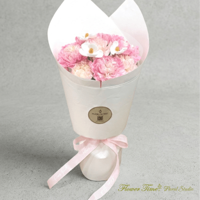 Pink and white bouquet wrapped in white paper with a pink ribbon