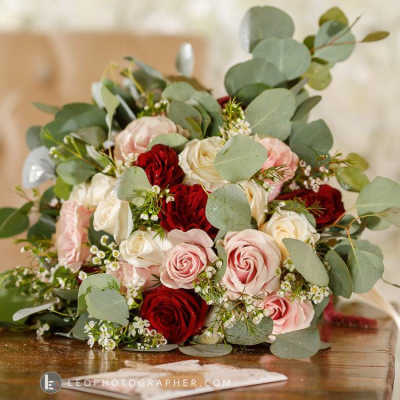 Bouquet of red, pink, and white roses with eucalyptus