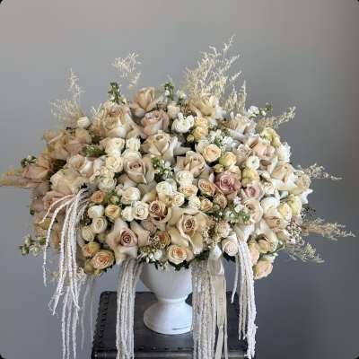 Large cream and blush rose arrangement in a white urn vase