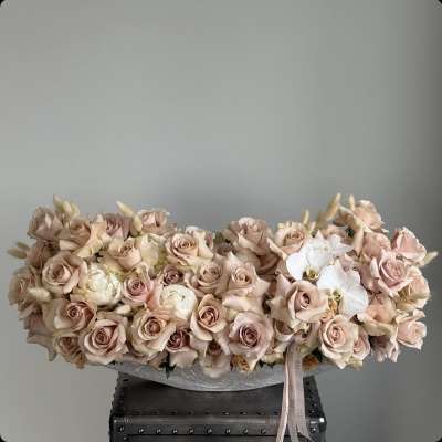 Low arrangement of blush roses and white orchids in a shallow container