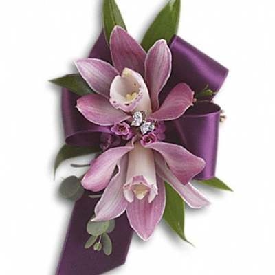 Purple orchid corsage with ribbon and green leaves