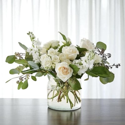 White roses and white blooms in a clear glass vase