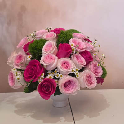 Pink and magenta roses arranged in a white vase