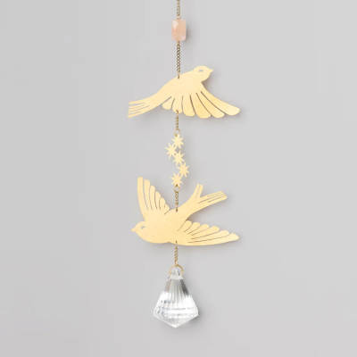 Hanging decor with two gold bird cutouts and a clear faceted crystal on a chain.
