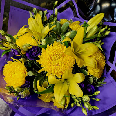 Yellow lilies and chrysanthemums with purple flowers wrapped in purple paper